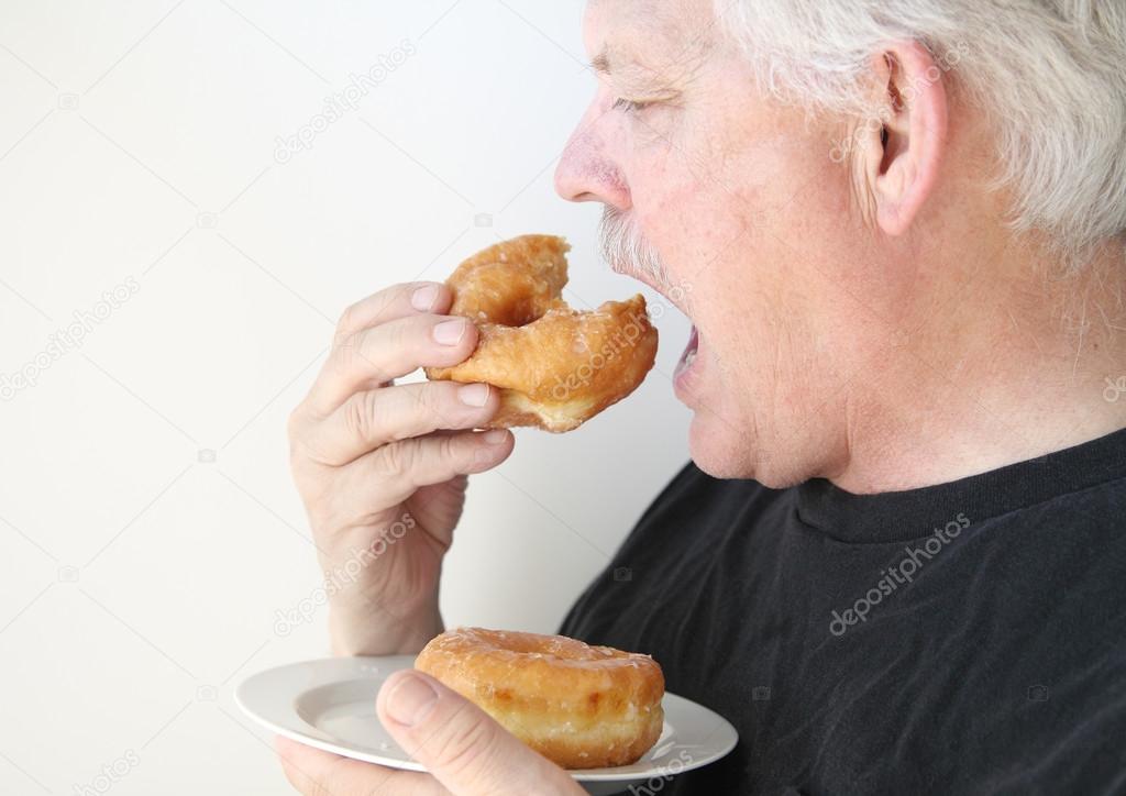 Older man eats glazed doughnut