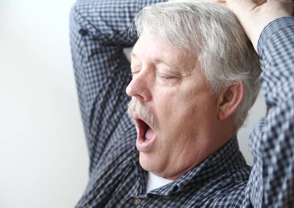 Sleepy older man yawns