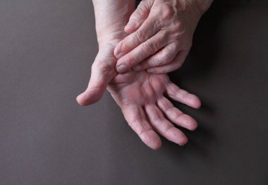 An older man indicates an area of pain on his thumb 