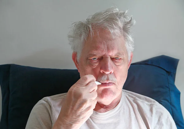 Malade Homme Âgé Penche Sur Oreiller Avec Thermomètre Dans Bouche Images De Stock Libres De Droits