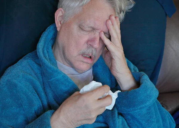 Älterer Mann Hält Kopf Und Taschentuch Auf Dem Sofa Stockfoto