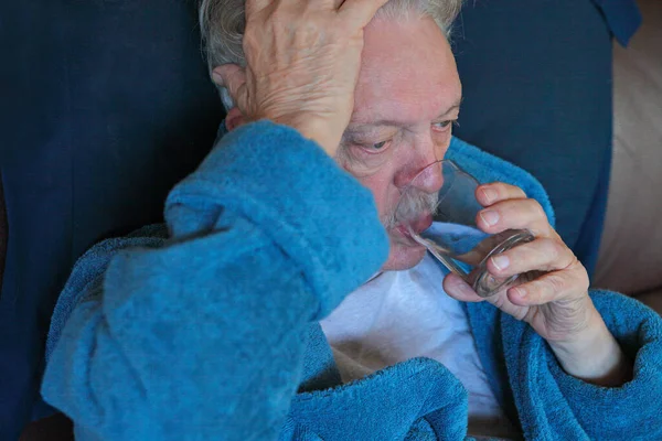 Senior Bademantel Mit Hand Auf Dem Kopf Trinkt Glas Wasser lizenzfreie Stockbilder