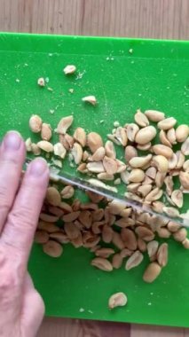 Yeşil kesme tahtasına fıstık kesen bir kadının dikey görüntüsü