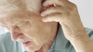 Yaşlı adam kulağına işitme cihazı yerleştirir.