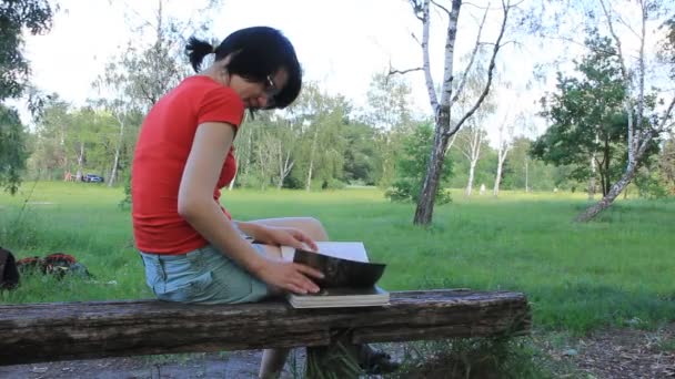 Dziewczyna czyta książkę w parku — Wideo stockowe