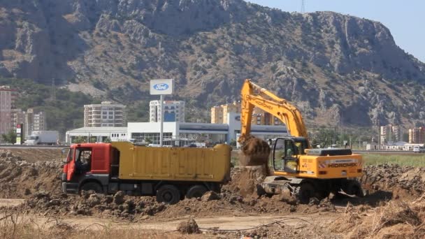 Excavadora amarilla y camión volquete — Vídeos de Stock