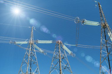 Üç büyük elektrik iletim kulesi ve güneş ışığı