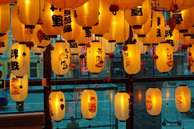 UKRAINE, KYIV, APRIL 21, 2022: Ukrayna 'nın başkenti Kyiv' in merkezindeki bir Asya restoranında sarı Çin fenerleri, restoranın içinden otomobil trafiği ile yol manzarası