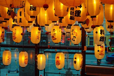 UKRAINE, KYIV, APRIL 21, 2022: Ukrayna 'nın başkenti Kyiv' in merkezindeki bir Asya restoranında sarı Çin fenerleri, restoranın içinden otomobil trafiği ile yol manzarası