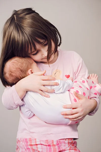 Chica feliz sosteniendo a su hermana recién nacida —  Fotos de Stock