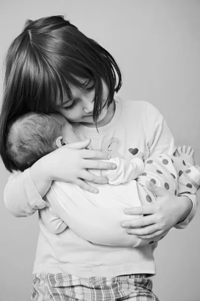 Happy girl holding her newborn sister Stock Image