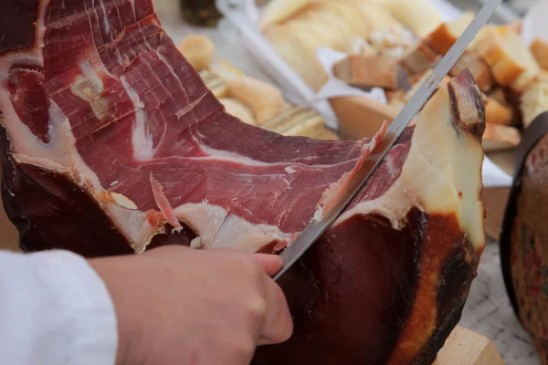 A hand cutting prosciutto — Stock Photo, Image