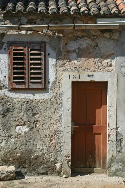 Porta de madeira e janela na parede de pedra, fachada de construção, Pag, Croácia — Fotografia de Stock