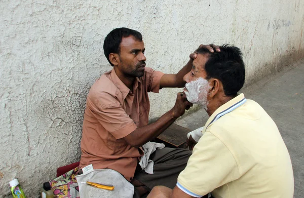 Стрит парикмахер бреет мужчину на улице в Калькутте, Западная Бенгалия, Индия — стоковое фото