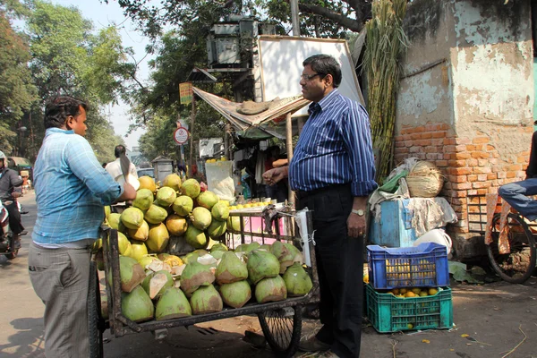 Säljaren säljer kokosnötter på utomhusmarknad, kolkata, Indien — Stockfoto
