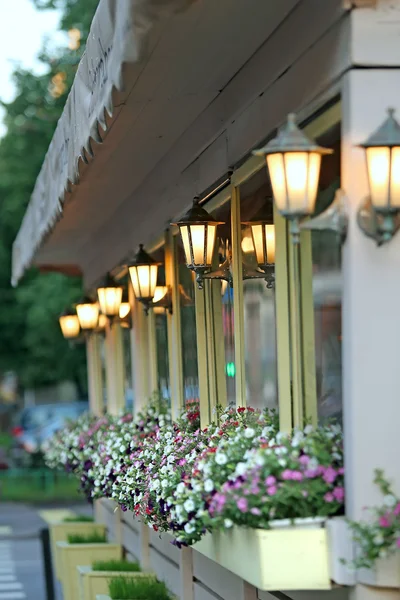 Ściany domu z lampy i kwiaty petunii — Zdjęcie stockowe