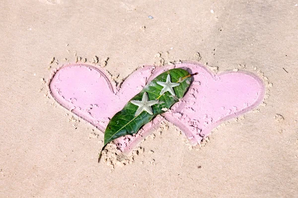 Drawn hearts and starfishes on wet sand — Stock Photo, Image