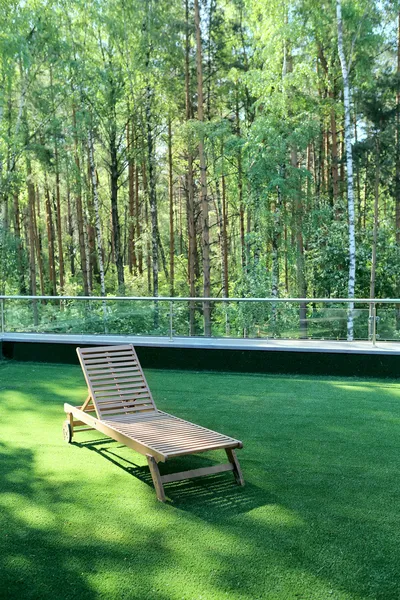Chaise longue en bois sur herbe près de bouleau — Photo