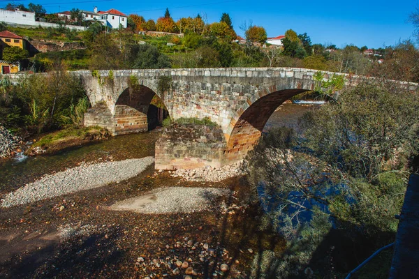 Portekiz 'de sonbaharda sığ bir nehrin üzerindeki ortaçağ kemer köprüsü