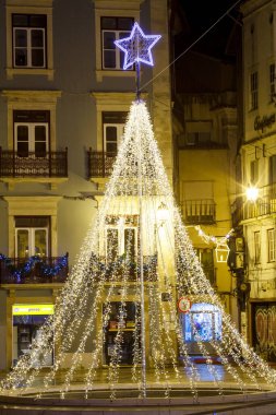 Geceleyin sokakta aydınlanan yılbaşı ağacı Portekiz 'in eski bir kasabasının caddesinde