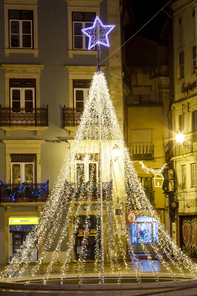 Geceleyin sokakta aydınlanan yılbaşı ağacı Portekiz 'in eski bir kasabasının caddesinde