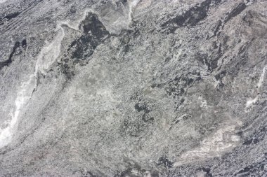 An abstract pattern of a layered section of a stone. Background in white, gray and black shades.