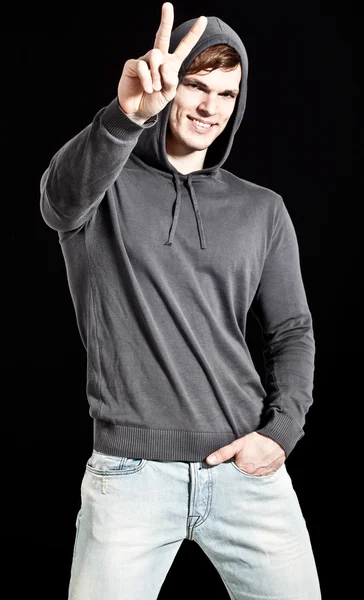 Young attractive happy man wearing gray sweater with hood - show — Stock Photo, Image