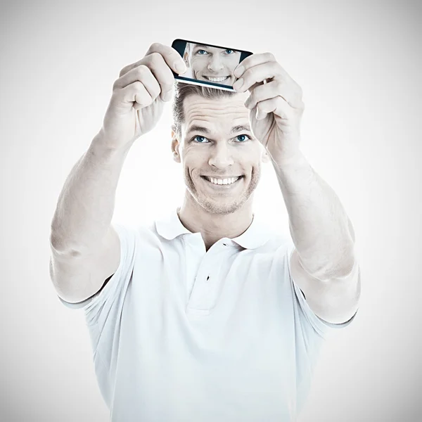 Casual young man smiles into his smartphone while taking a selfie — Stock Photo, Image