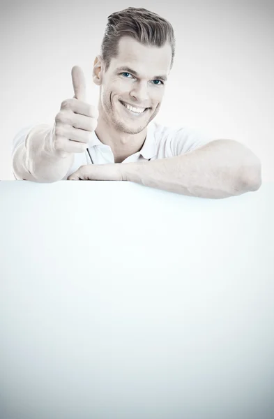 Young man standing behind a whiteboard and showing thumb up — Stock Photo, Image