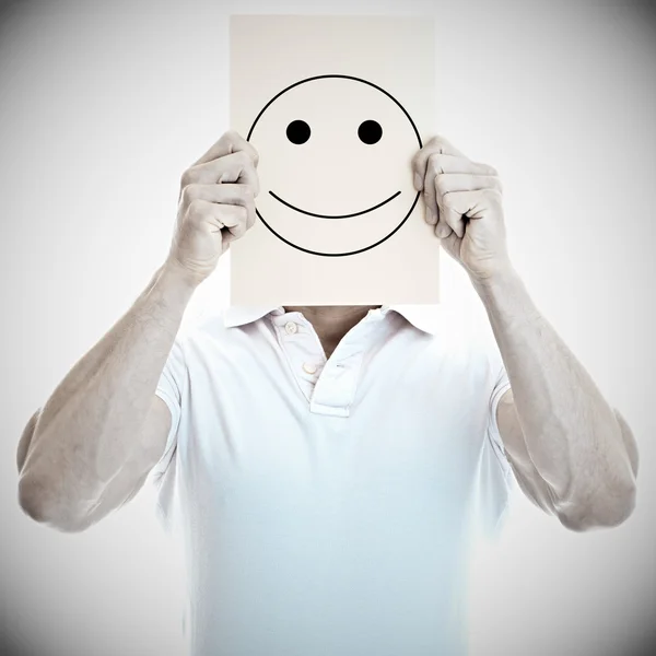 Joven con una feliz tarjeta sonriente cubriendo fac — Foto de Stock