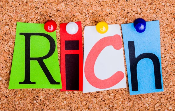 The word Rich in cut out magazine letters pinned to a cork notic — Stock Photo, Image