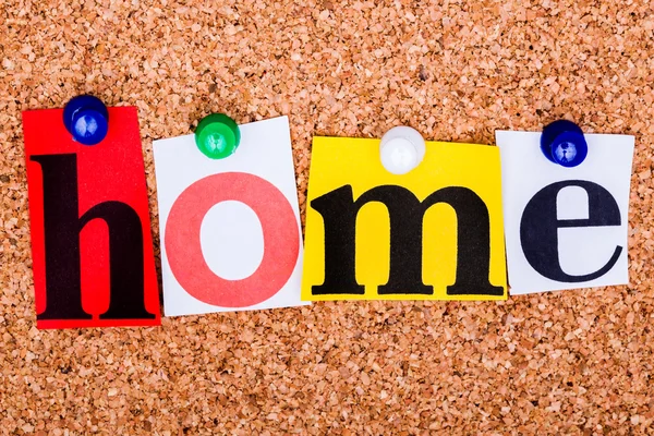 The word Home in cut out magazine letters pinned to a cork notic — Stock Photo, Image