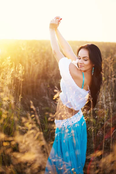 Krásná žena v poli při západu slunce — Stock fotografie