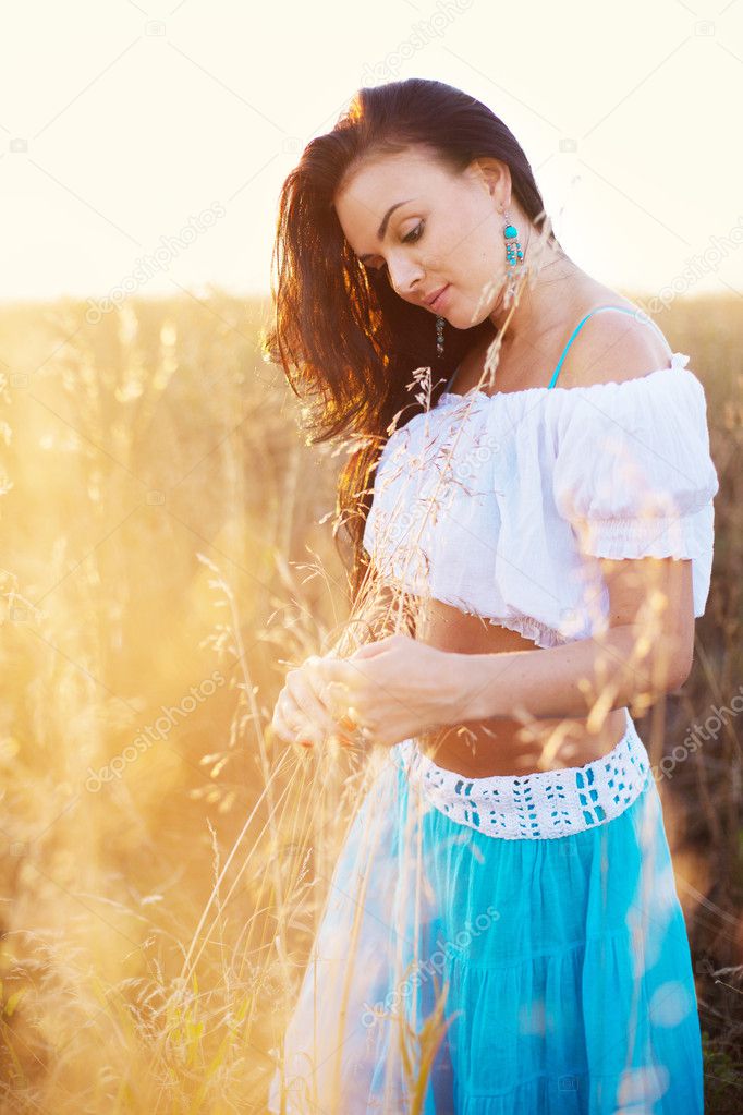 Beautiful woman in field at sunset