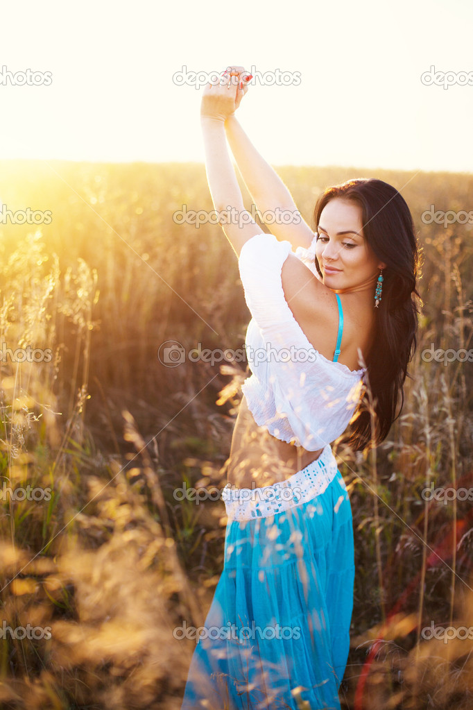 Beautiful woman in field at sunset
