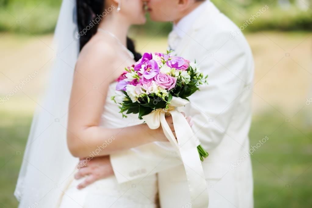 Kissing couple and wedding bouquet