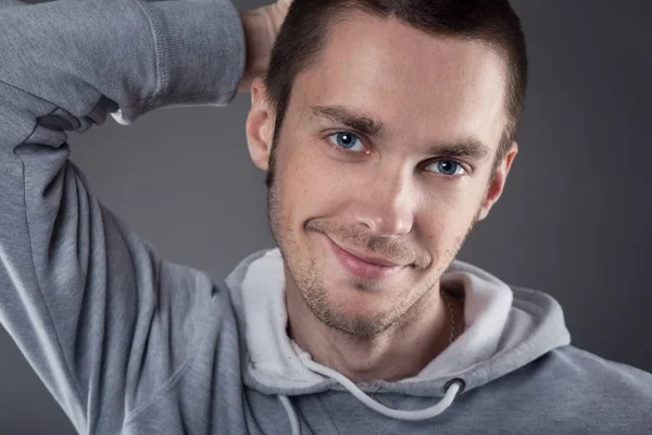 Closeup of young man with hand on head on gray background — Stock Photo, Image