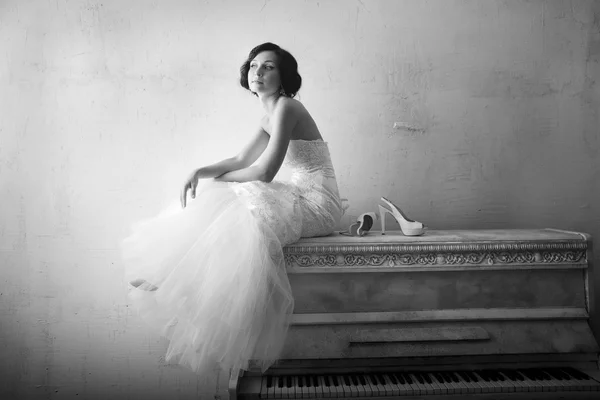 Mulher bonita sentada em um piano branco. Estilo retrô — Fotografia de Stock