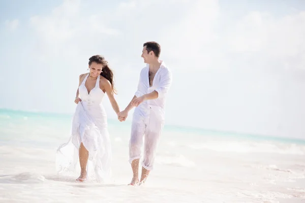 Casal recém-casado correndo em uma praia tropical — Fotografia de Stock