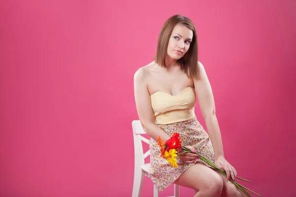 Ritratto di ragazza carina adolescente che tiene fiori su sfondo rosa studio — Foto Stock