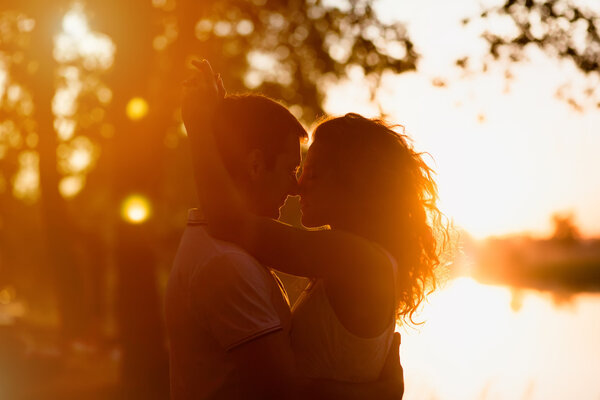 молодая красивая пара обнимается на белом фоне заката
