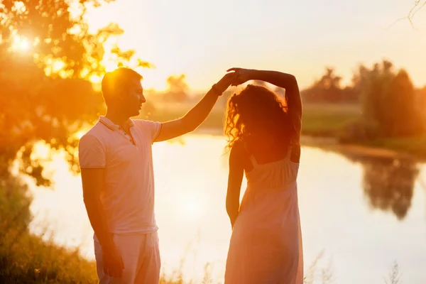 Jeune beau couple en danse blanche sur fond de coucher de soleil — Photo