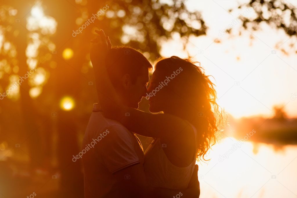 young beautiful couple embracing on a white background of a sunset