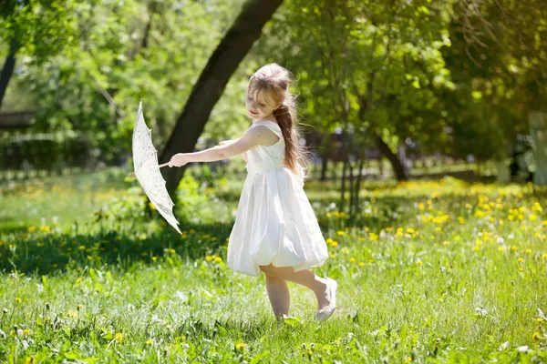 Flicka med en sommar spetsar paraply spelar i parken — Stockfoto