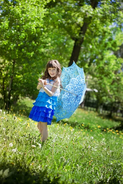 Kleines Mädchen mit blauem Spitzenschirm spaziert durch den Park — Stockfoto