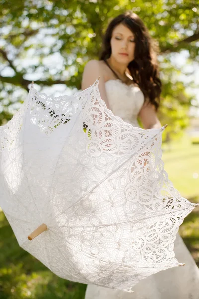 Bride is holding a cookie lace umbrella, focus point on the umbrella — Stock Photo, Image