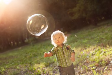 küçük çocuk günbatımında sabun köpüğü yakalar