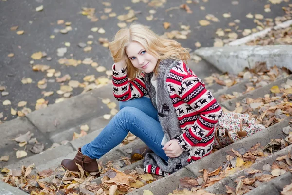 Girl sitting on the stairs in the autumn park — Stock Photo, Image