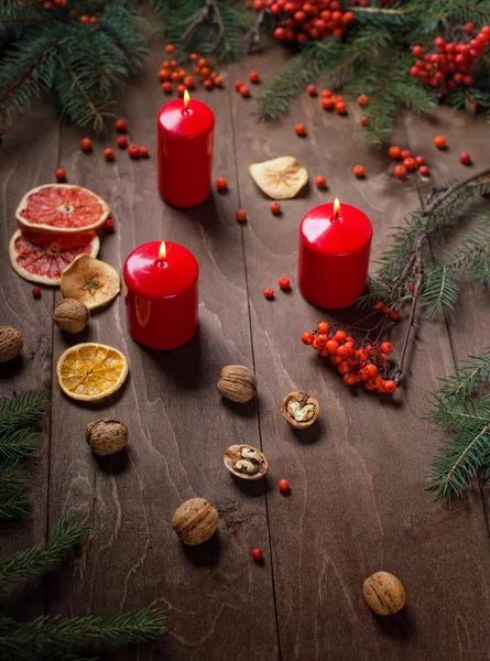 Christmas candles and fir tree branches on a wooden background — Stock Photo, Image