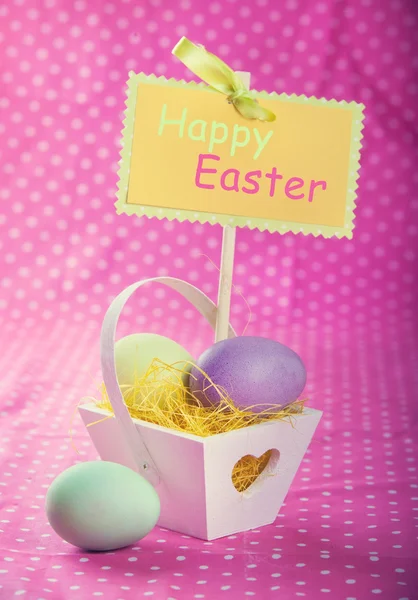 Huevos de Pascua coloridos en una cesta decorativa en el fondo de mantel púrpura —  Fotos de Stock